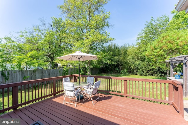 wooden deck featuring a yard, outdoor dining space, and a fenced backyard