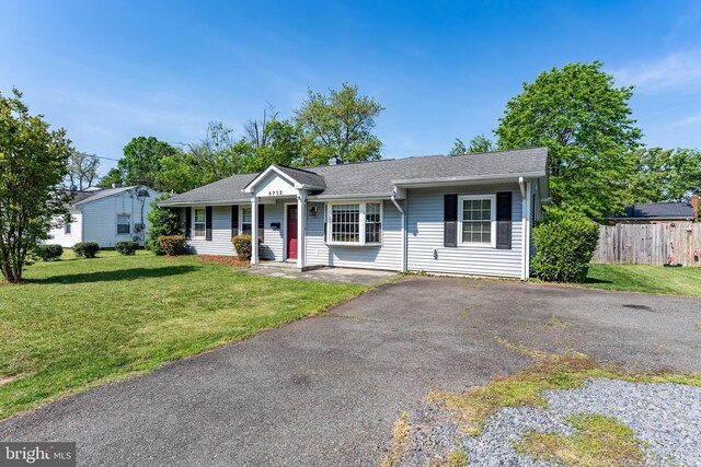 single story home featuring a shingled roof, fence, and a front yard