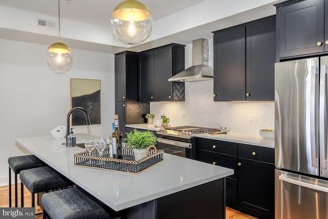 426 Manor Pl NW Unit 2, Washington, DC 20010 - kitchen featuring dark cabinetry, wall chimney range hood, stainless steel appliances, and decorative backsplash
