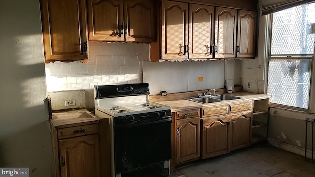 kitchen with electric range, a sink, light countertops, freestanding refrigerator, and backsplash