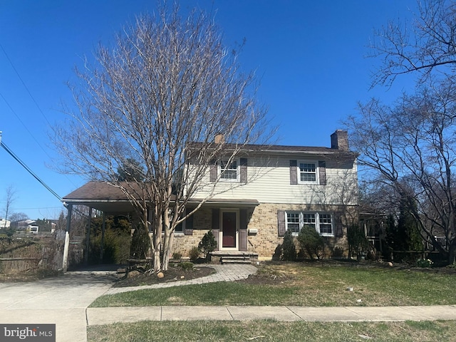 traditional-style house with a carport, a chimney, driveway, and a front lawn