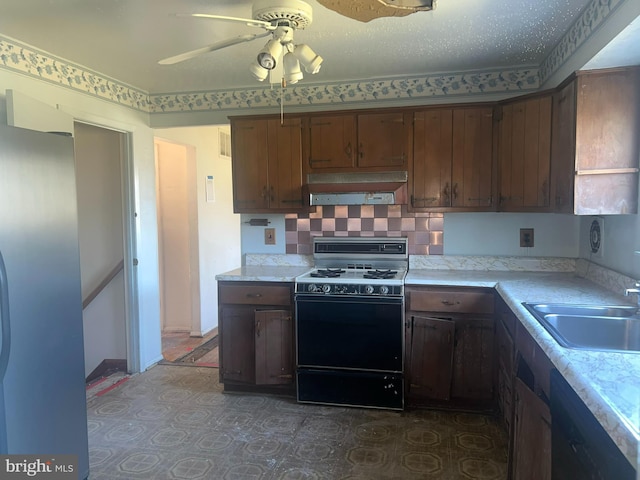kitchen featuring a ceiling fan, a sink, light countertops, under cabinet range hood, and gas range oven