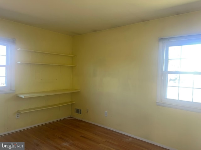 empty room with baseboards, visible vents, and wood finished floors