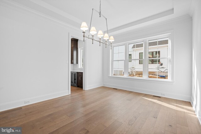 unfurnished dining area with a chandelier, light wood-style flooring, baseboards, visible vents, and ornamental molding