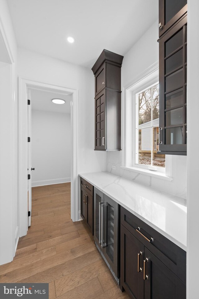 bar featuring light wood-type flooring, recessed lighting, baseboards, and beverage cooler