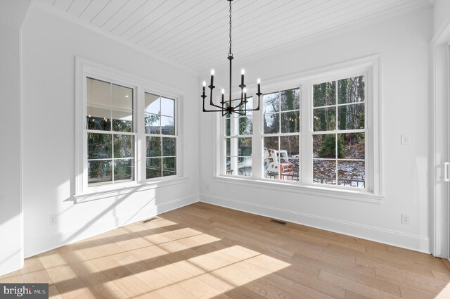 unfurnished dining area with crown molding, an inviting chandelier, and a healthy amount of sunlight