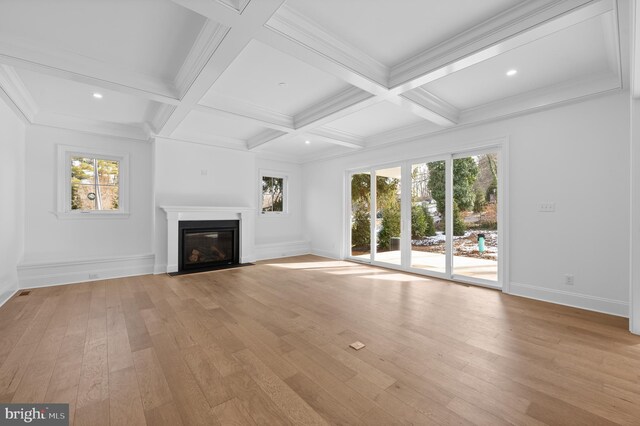 unfurnished living room featuring a fireplace with flush hearth, light wood finished floors, a wealth of natural light, and beamed ceiling