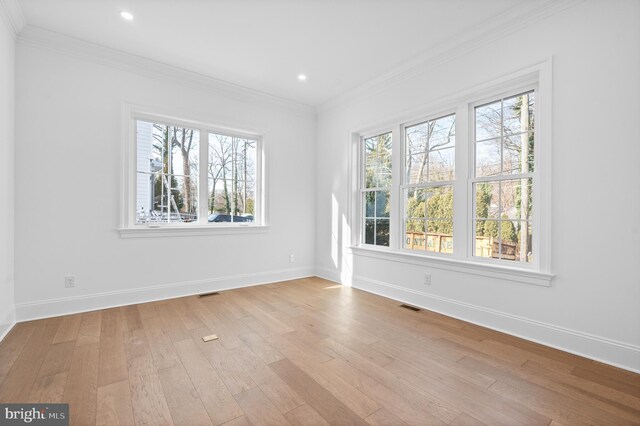 empty room featuring crown molding, visible vents, plenty of natural light, and light wood-style flooring