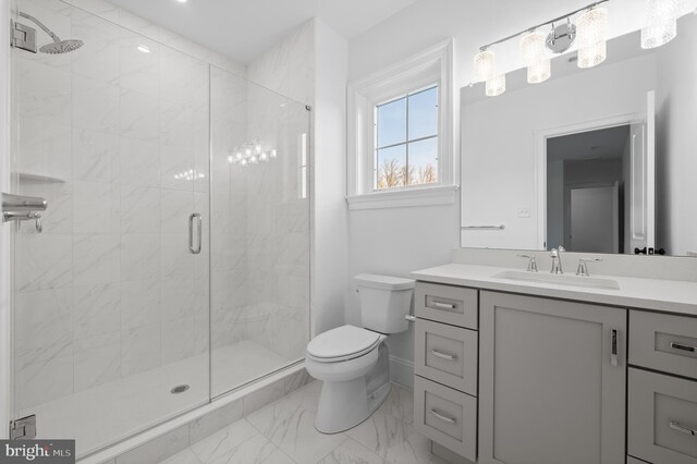 bathroom featuring vanity, toilet, marble finish floor, baseboards, and a stall shower