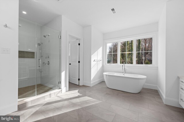 bathroom with baseboards, visible vents, a soaking tub, and a stall shower