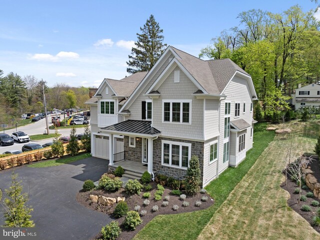 view of front of house with an attached garage, a shingled roof, stone siding, and aphalt driveway