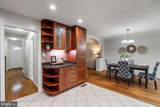 2192 Golf Course Dr, Reston, VA 20191 - kitchen featuring open shelves, arched walkways, brown cabinetry, light wood-type flooring, and crown molding