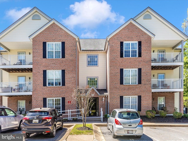 view of property with brick siding and uncovered parking