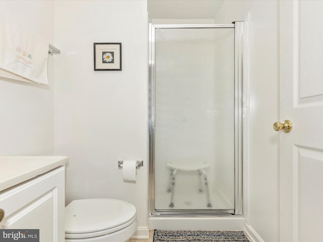 bathroom featuring baseboards, vanity, toilet, and a shower stall