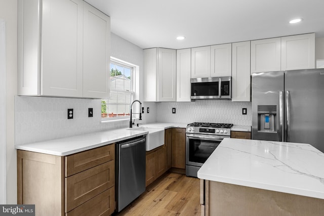183 Mccormick Blvd, Newark, DE 19702 - kitchen with stainless steel appliances, light wood finished floors, light stone counters, decorative backsplash, and white cabinetry