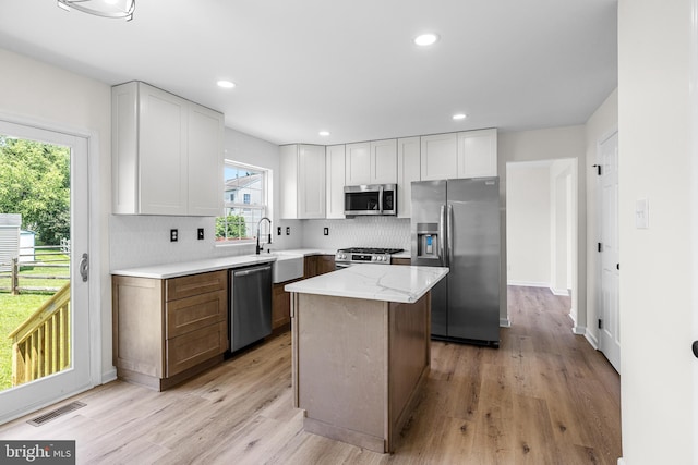 183 Mccormick Blvd, Newark, DE 19702 - kitchen featuring appliances with stainless steel finishes, white cabinetry, tasteful backsplash, light wood-style flooring, and a center island