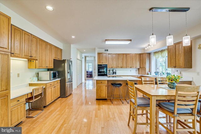 30 Revere Ct, Princeton Junction, NJ 08550 - kitchen featuring stainless steel appliances, light countertops, a breakfast bar, light wood-style floors, and a center island