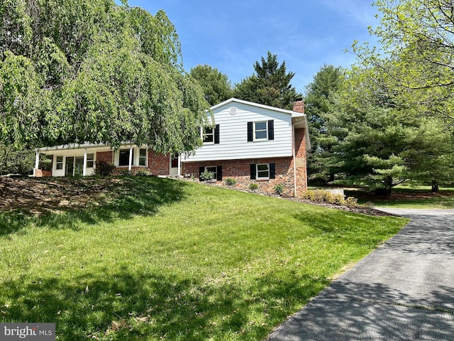 tri-level home featuring brick siding, a front lawn, and a chimney