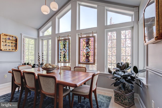 dining area featuring baseboards, vaulted ceiling, and wood finished floors