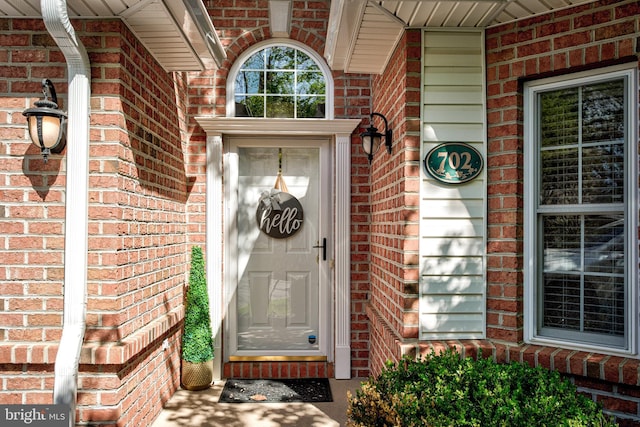 entrance to property with a porch and brick siding