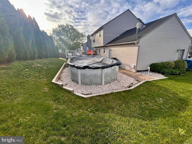rear view of house featuring a wooden deck, a yard, and a covered pool