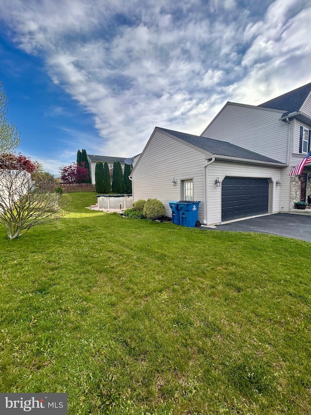 view of side of property featuring an attached garage, a yard, and driveway