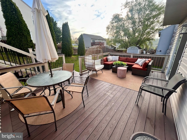 deck featuring an outdoor hangout area, a storage shed, a fenced backyard, an outbuilding, and outdoor dining area