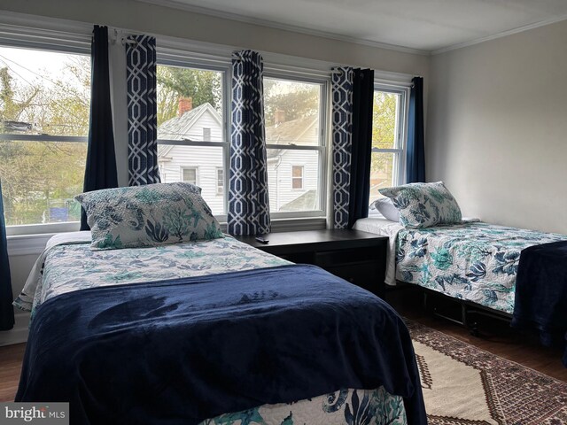 bedroom with crown molding, wood finished floors, and multiple windows
