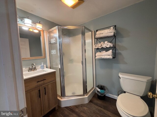 bathroom featuring vanity, wood finished floors, toilet, and a shower stall