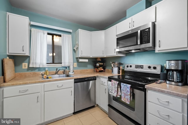 kitchen with a sink, light countertops, stainless steel appliances, white cabinetry, and light tile patterned floors