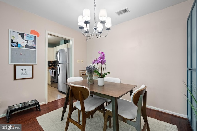 dining space featuring visible vents, baseboards, wood finished floors, and an inviting chandelier