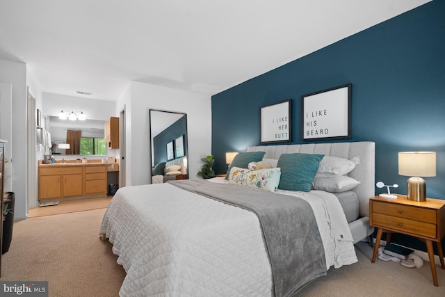 bedroom featuring visible vents, light carpet, and ensuite bathroom