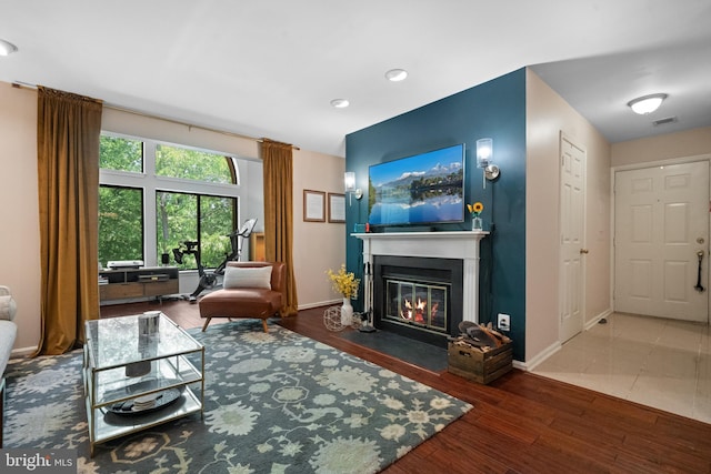 living room featuring visible vents, a fireplace with flush hearth, wood finished floors, baseboards, and recessed lighting