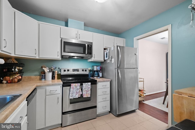 kitchen featuring light countertops, stainless steel appliances, white cabinetry, and light tile patterned flooring