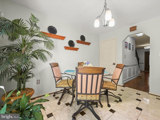 dining area featuring stairs, arched walkways, baseboards, and light tile patterned floors