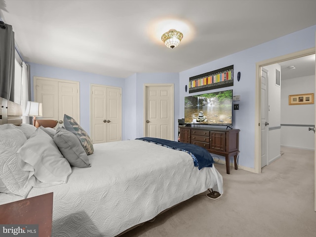 bedroom with multiple closets, baseboards, light colored carpet, and visible vents