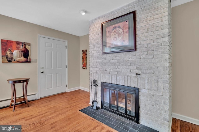 living area featuring baseboards, a baseboard heating unit, wood finished floors, and a fireplace