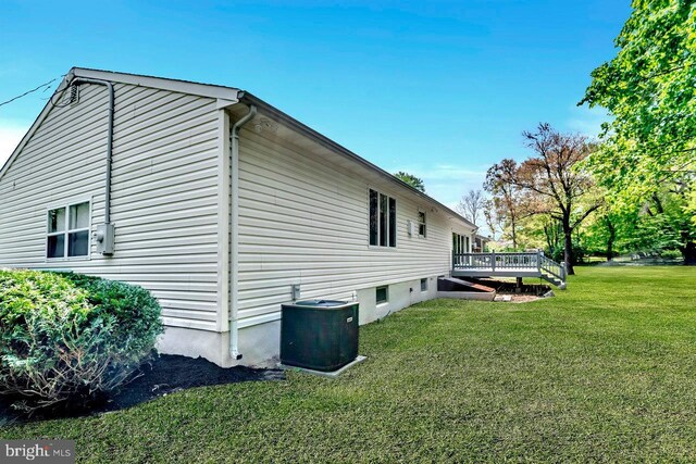 view of side of property featuring a yard, a deck, and central AC