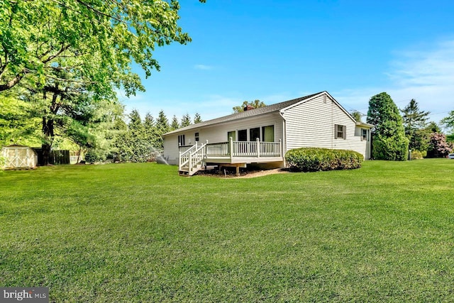 back of property featuring a lawn, a deck, an outdoor structure, and a storage unit