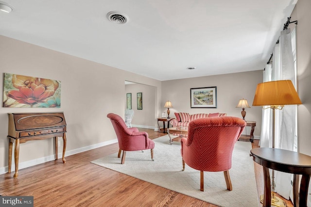 living area featuring baseboards, visible vents, and wood finished floors