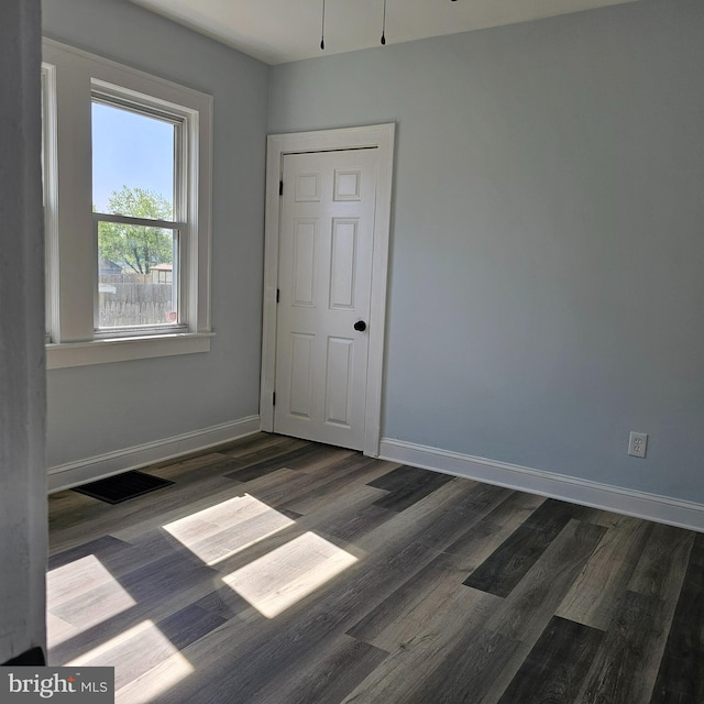 spare room with baseboards, wood finished floors, and visible vents