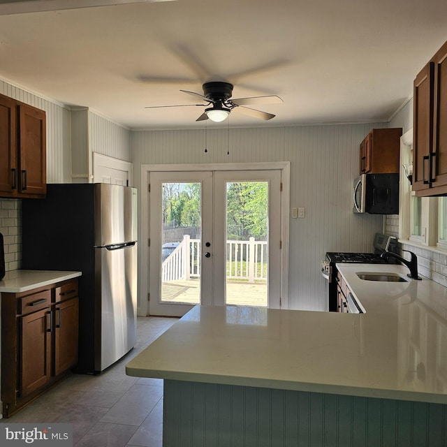 kitchen with a ceiling fan, french doors, appliances with stainless steel finishes, a sink, and a peninsula