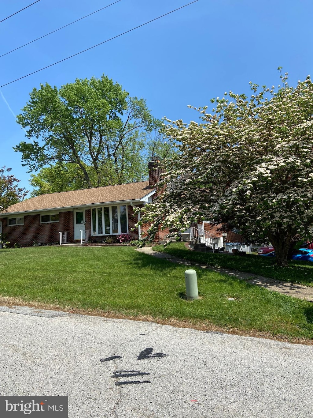 single story home with brick siding, a chimney, and a front yard