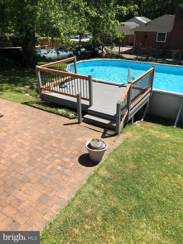 pool featuring a yard, fence, and a wooden deck