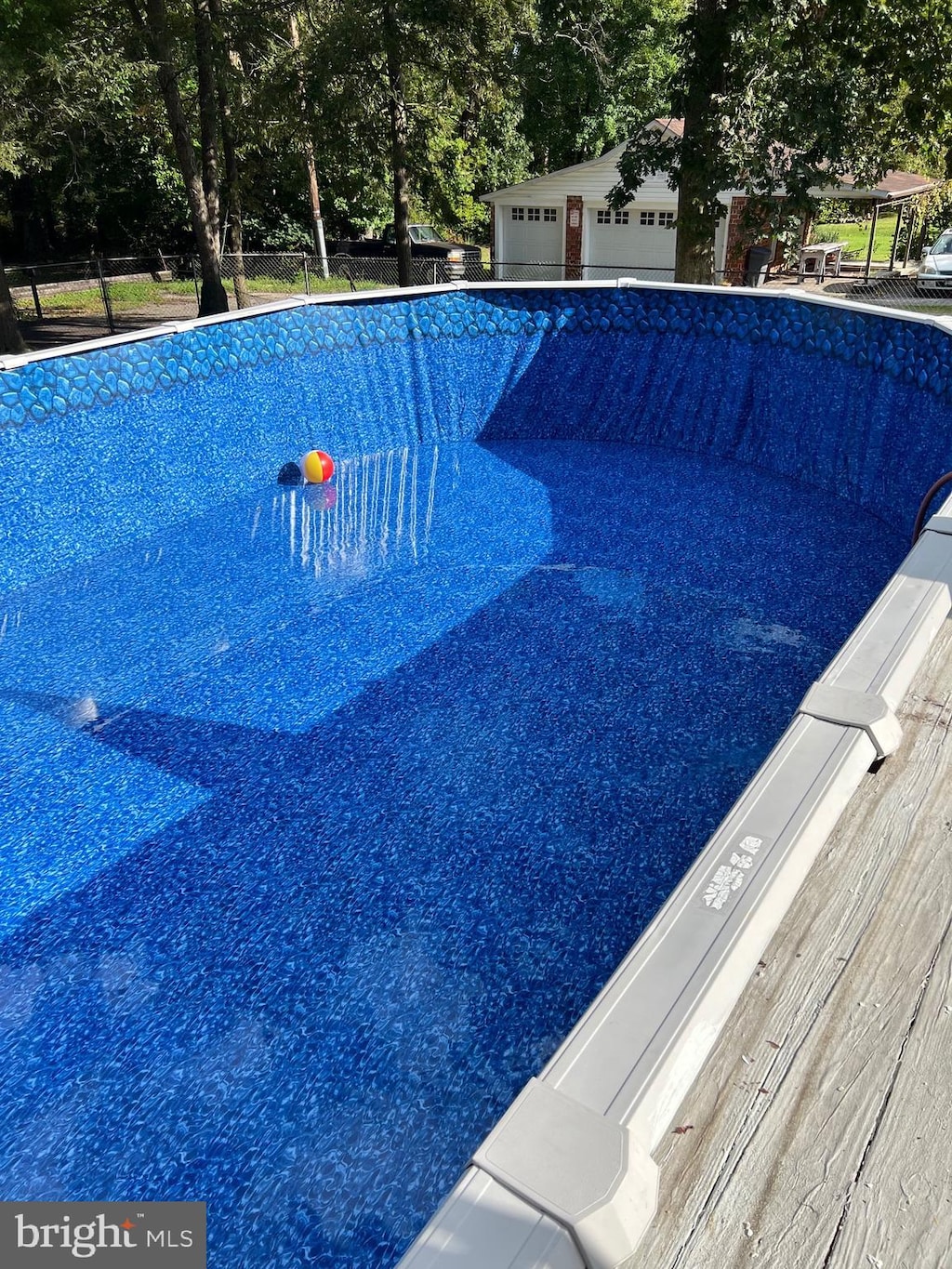 view of swimming pool with fence and an empty pool