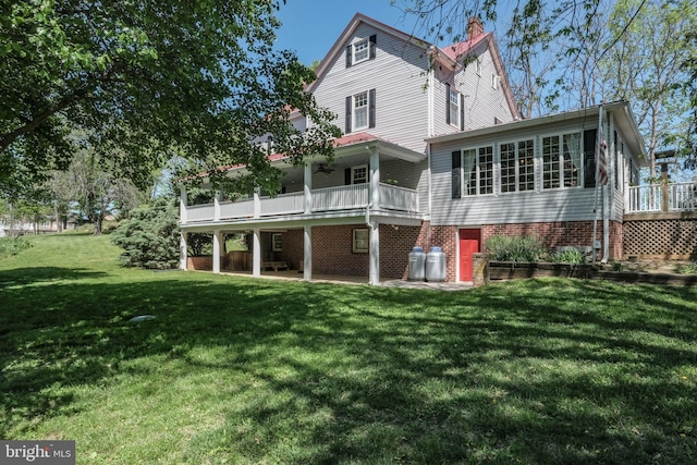 rear view of property featuring a lawn, a chimney, and a wooden deck