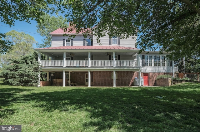 rear view of house featuring a ceiling fan, a wooden deck, a yard, and metal roof