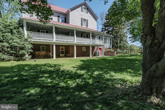 rear view of property with central AC, a standing seam roof, a ceiling fan, metal roof, and a yard