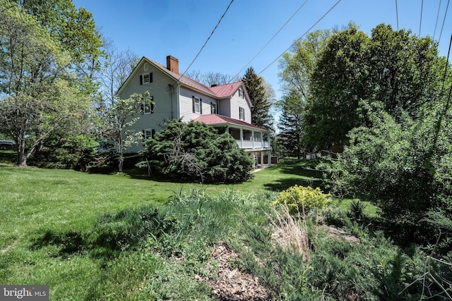 view of home's exterior featuring a standing seam roof, a yard, a chimney, and metal roof