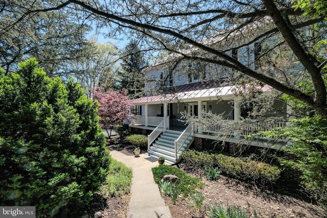 view of front of house with a standing seam roof, covered porch, stairs, and metal roof